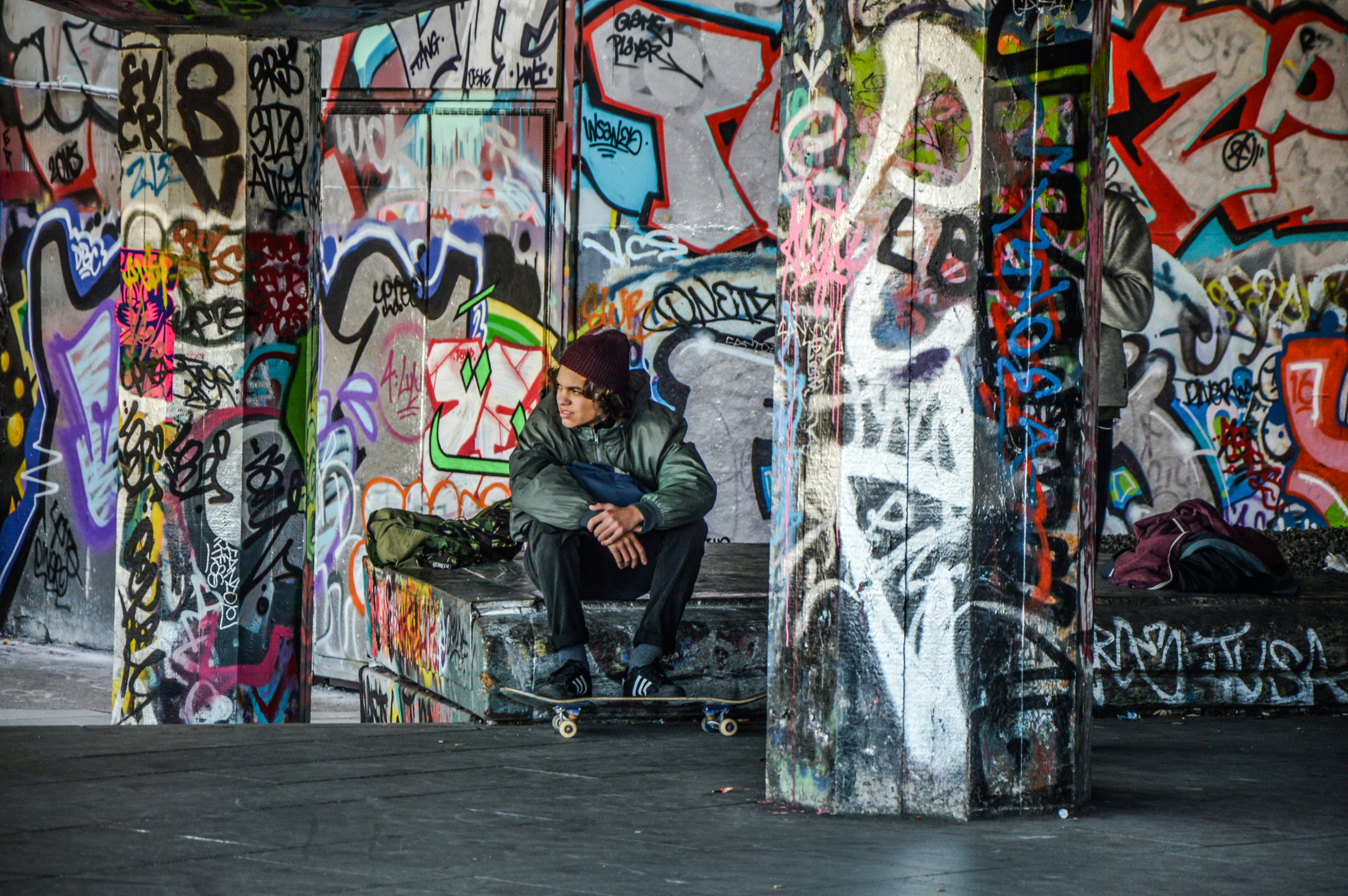 Skateboarder hanging out amongst graffiti.